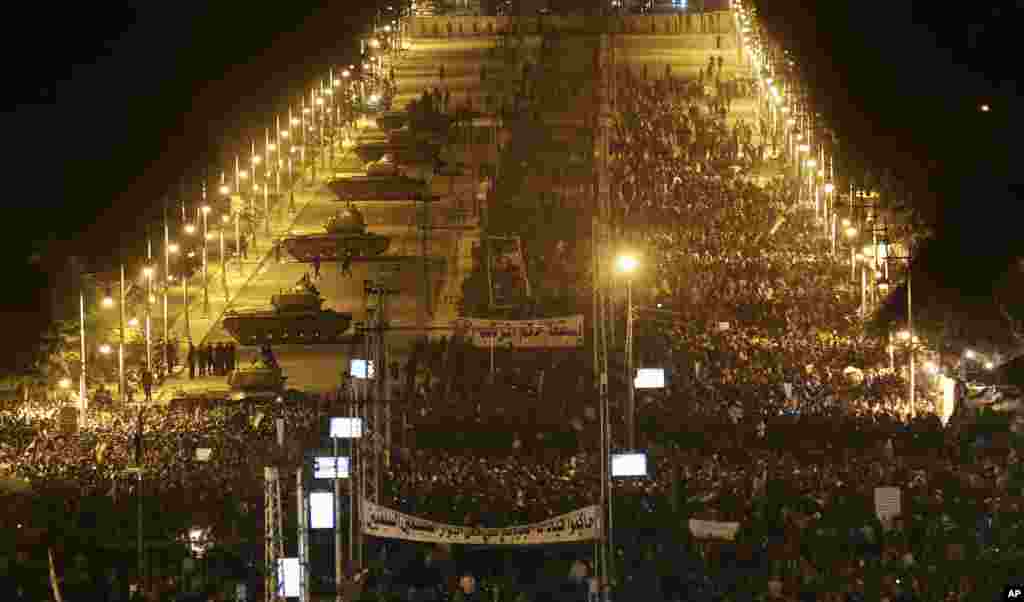 Army tanks, left, deploy as Egyptian protesters gather outside the presidential palace during a demonstration against President Mohamed Morsi in Cairo, Egypt, December 11, 2012.