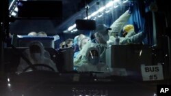 Australian passengers disembarked from the quarantined Diamond Princess cruise ship, wave from the bus as they leave a port Wednesday, Feb. 19, 2020, in Yokohama, near Tokyo.