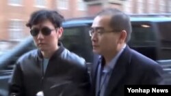 FILE - Thae Yong Ho, right, escorts North Korean leader Kim Jong Un's elder brother, Kim Jong Chol, to an Eric Clapton concert in London in 2015, in this image from Japanese TBS TV. Thae has defected to South Korea, Seoul officials say.