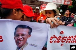 FILE - Cambodia garment workers hold banners with a portrait of Prime Minister Hun Sen while authority prevent them from reaching the prime minister's residence in Phnom Penh, Cambodia.