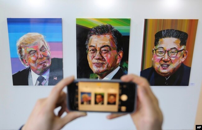 FILE - A visitor takes images, from left, of U.S. President Donald Trump, South Korean President Moon Jae-in and North Korean leader Kim Jong Un during an exhibition at an annex of the presidential Blue House in Seoul, South Korea, Jan. 3, 2019.