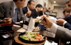 Lawmakers and government officials try whale meat dishes to promote whale meat at a dining room of Ministry of International Trade and Industry in Tokyo Wednesday, Nov. 19, 2014.