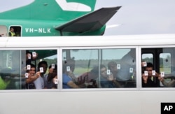 FILE - In this Aug. 2, 2013 photo, a group of asylum seekers hold up their identity after landing in Manus Island, Papua New Guinea.