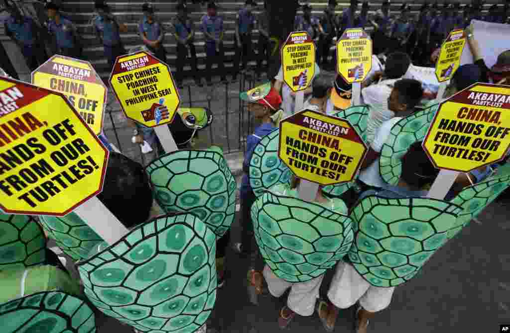 Police face off with demonstrators dressed as green sea turtles protesting recent poaching by China during a rally in front of the Chinese consulate at the financial district of Makati city, Philippines, May 16, 2014.