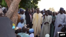 A villager speaks standing next to the governor of Borno State, Kashim Shettima (C), during Shettima's visit to Benisheik, on September 19, 2013, after a violent attack by Boko Haram Islamists kills at least 87 people.
