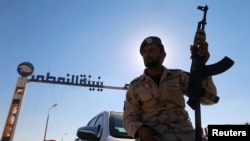 FILE - A member of Libyan forces loyal to eastern commander Khalifa Haftar holds a weapon as he sits on a car in front of the gate at Zueitina oil terminal in Zueitina, west of Benghazi, Libya, Sept. 14, 2016. 