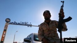 A member of Libyan forces holds a weapon as he sits on a car in front of the gate at Zueitina oil terminal in Zueitina, west of Benghazi, Libya, Sept. 14, 2016. 