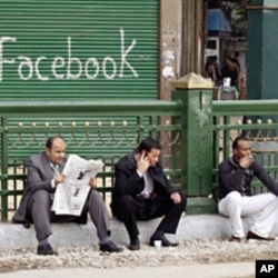 Anti-government protesters sit next to a "Facebook" graffiti sign during demonstrations inside Tahrir Square in Cairo (File)