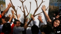 Environmentalists make symbolic hand prints on a tree wall prior to a coastal clean up to mark World Earth Day Friday, April 22, 2016 at a bird sanctuary known as "Freedom Island" in suburban Las Pians city, south of Manila, Philippines. 