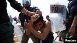 Policemen detain a man during clashes with garment workers in Phnom Penh, Nov. 12, 2013. 