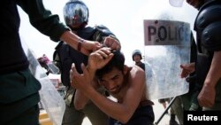 Policemen detain a man during clashes with garment workers in Phnom Penh, Nov. 12, 2013. 