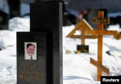FILE - A picture of lawyer Sergei Magnitsky is seen on his grave in the Preobrazhensky cemetery in Moscow, March 11, 2013.