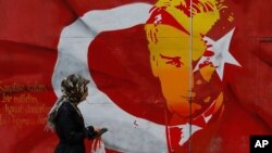 A woman walks past a billboard with a Turkish flag decorated with an image of Turkey's founder Kemal Ataturk, in Istanbul, April 12, 2017. Turkey is heading to a contentious April 16 referendum on constitutional reforms to expand President Recep Tayyip Erdogan's powers.