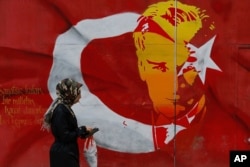 A woman walks past a billboard with a Turkish flag decorated with an image of Turkey's founder Kemal Ataturk, in Istanbul, April 12, 2017.