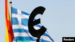 FILE - A Greek flag flies behind a statue to European unity outside the European Parliament in Brussels.