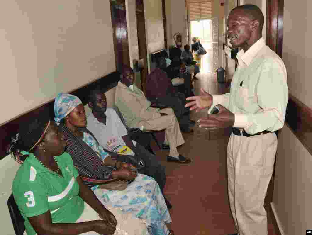 FILE - A health worker from The AIDS Support Organization (TASO) speaks with patients waiting for treatment in Kampala, Uganda.