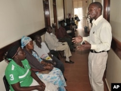 FILE - A health worker from The AIDS Support Organization (TASO) speaks with patients waiting for treatment in Kampala, Uganda, July 12, 2012.