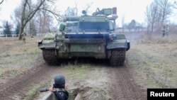 A reservist of the Ukrainian Territorial Defense Forces throws a dummy grenade towards an armored vehicle during military exercises at a training ground outside Kharkiv, Ukraine Dec. 11, 2021.