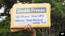 A member of a civic group holds a sign before a rally against the South Korea-U.S. Joint military drills near the presidential Blue House in Seoul, South Korea, Aug. 21, 2017.