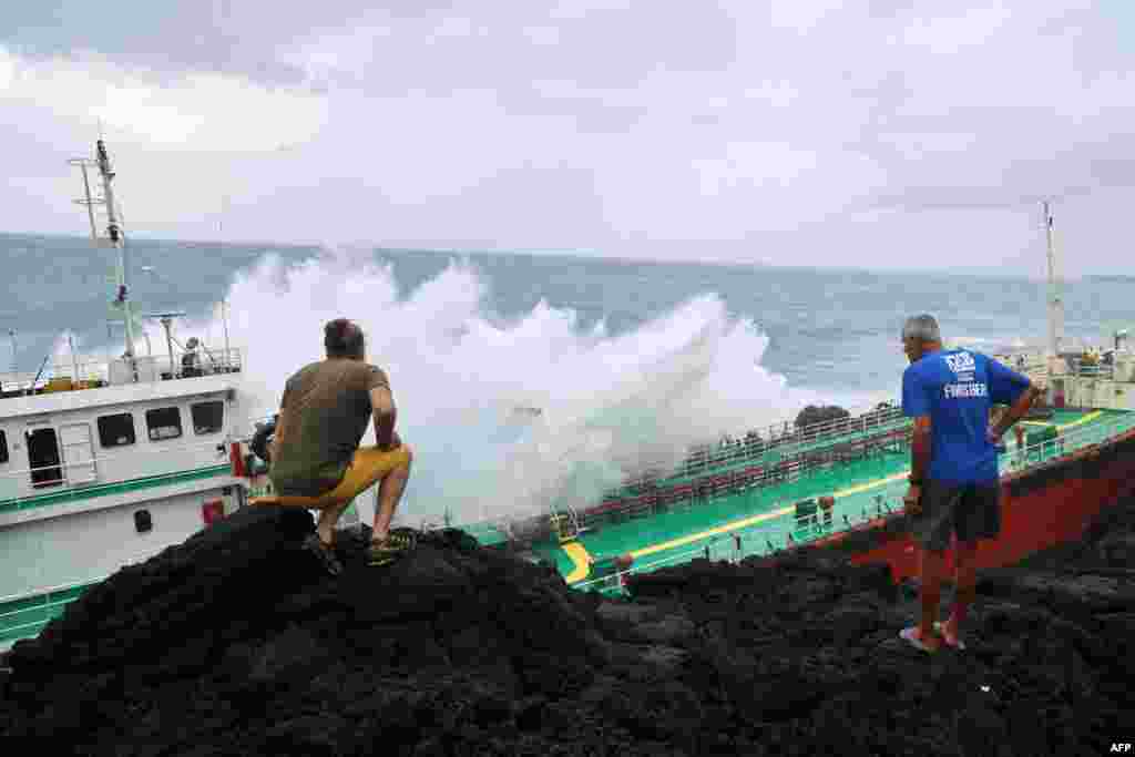 Pedestrians look at a Maurician oil tanker, Tresta Star, stranded on Tremblet coast in Saint-Philippe, south-east of the French Indian Ocean island of La Reunion, after the passage of Tropical Cyclone Batsirai.