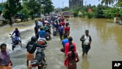People move past a flooded road in Thrissur, in the southern Indian state of Kerala, Aug. 17, 2018. 