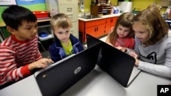 Elèves de deuxième année aidant des enfants de la maternelle à la programmation lors de leur leçon hebdomadaire d’informatique dans une école primaire américaine. (Photo AP)