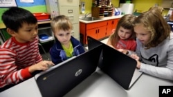 FILE - Second-grader Josh Mercado, left, helps kindergartner Erik Hodges, as second-grader Annabelle Davis, right, helps kindergartner Kaidyance Harris, on programming during their weekly computer science lesson at Marshall Elementary School in Marysville, Wash., Nov. 4, 2015.