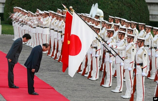 Thủ tướng Shinzo Abe (trái) và Thủ tướng Nguyễn Xuân Phúc cúi đầu trước quốc kỳ hai nước khi hai lãnh đạo có cuộc gặp tại Tokyo, Nhật Bản, vào ngày 6/6/2017.