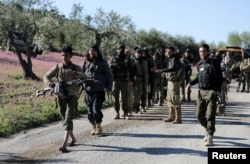 Turkish-backed Free Syrian Army fighters walk together after advancing north of Afrin, Syria, March 17, 2018.