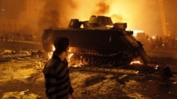 A protester watches as an Egyptian army vehicle burns in downtown Cairo on Friday