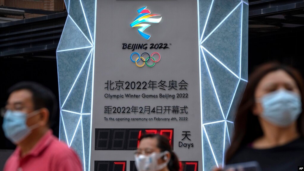 2021nian 8月18日，几名带口罩的民众走过一个2022年北京冬奥会倒计时看板。 (photo:VOA)