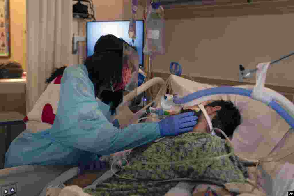 Patty Trejo, 54, touches the face of her husband, Joseph, in a COVID-19 unit at St. Jude Medical Center, in Fullerton, California, Feb. 15, 2021.