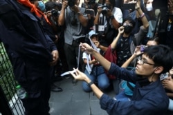 A protester makes a white ribbon as a symbol of peace in front of a police officer during anti-government protests in Bangkok, Thailand October 15, 2020. (REUTERS/Soe Zeya Tun)