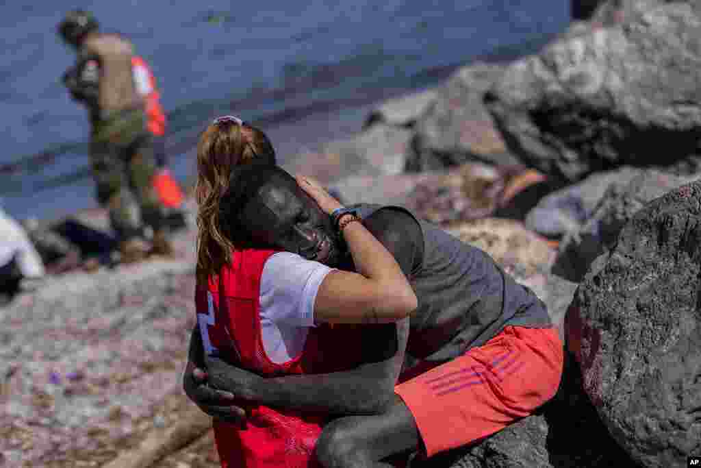 A migrant is comforted by a member of the Spanish Red Cross near the border of Morocco at the Spanish enclave of Ceuta, May 18, 2021. Thousands of Moroccans took advantage of relaxed border control in their country to swim or paddle into European soil.