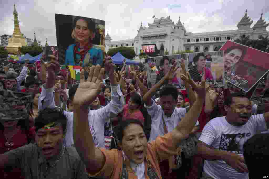 People hold the Myanmar national flag and placards as they attend a public gathering to listen to the live speech of Myanmar&#39;s State Counselor Aung San Suu Kyi in front of City Hall in Yangon.