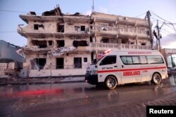 An ambulance passes in front of buildings damaged when a suicide car bomb exploded, targeting a Mogadishu hotel in a business center in Maka al-Mukaram street, Mogadishu, Somalia, March 1, 2019.