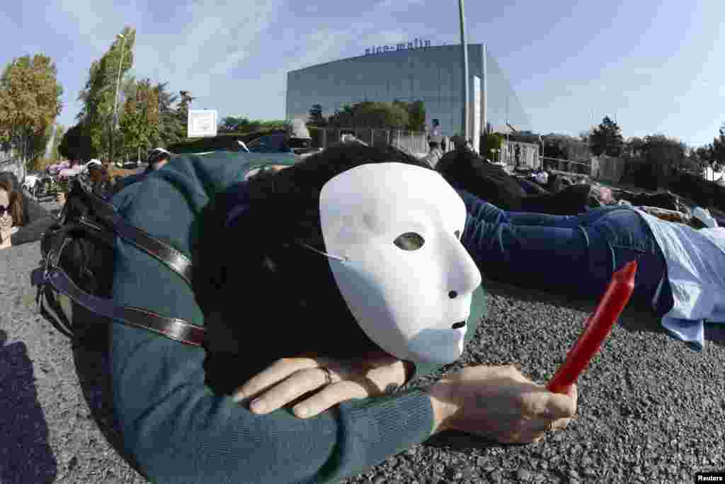 An employee at French newspaper Nice-Matin wears a mask and holds a candle as she lays on the road in front of their headquarters in Nice, as part of a demonstration by labor union members to symbolise the death of their jobs. 