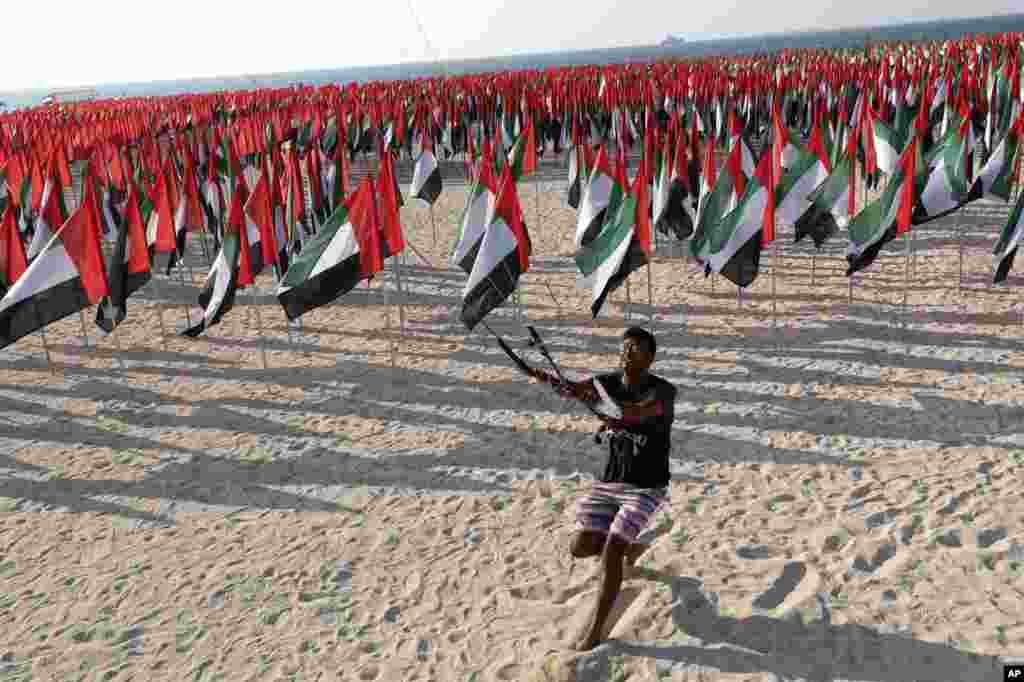 A man flies his kite in Dubai, where UAE national flags are set up to celebrate the country&#39;s Flag Day.