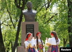 FILE - Girls react during the unveiling of a bust of Soviet dictator Joseph Stalin in the village of Trunovskoye in Stavropol region, Russia, May 5, 2017. A recent poll has found that 77 percent of respondents aged 18-24 years support similar Stalin memorials.