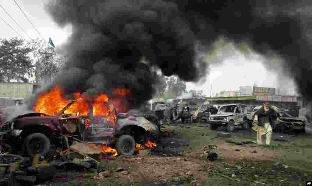 A man walks past a burning vehicle after a blast in Khyber, Pakistan, December 17, 2012.