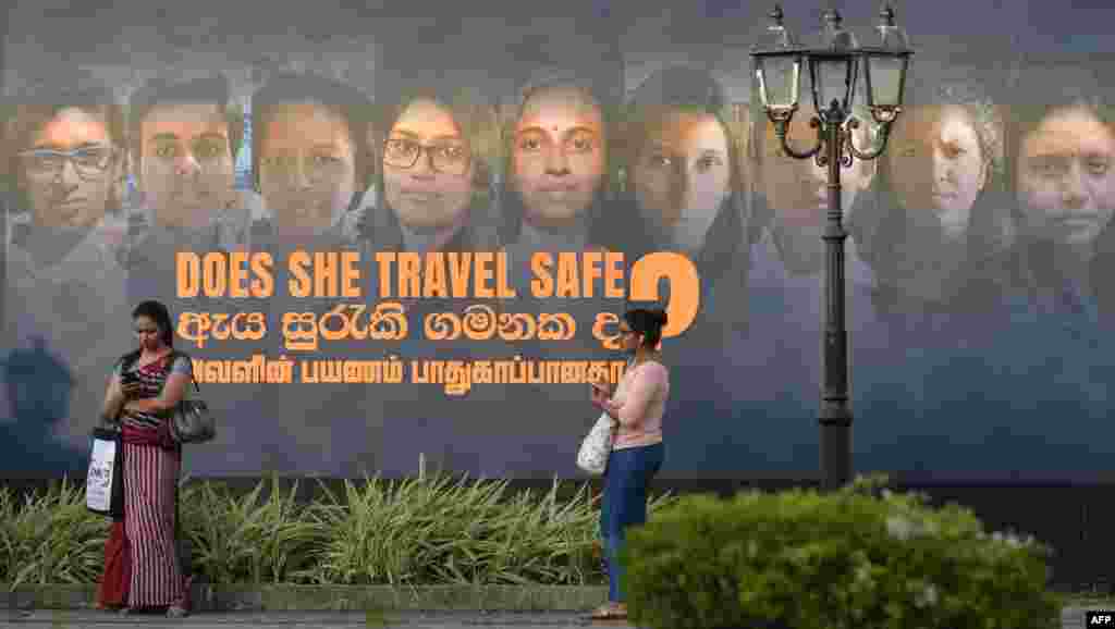 Women stand near a banner of an International Women's day photo exhibition in Colombo, Sri Lanka, ahead of International Women's Day, which is celebrated every year on March 8.