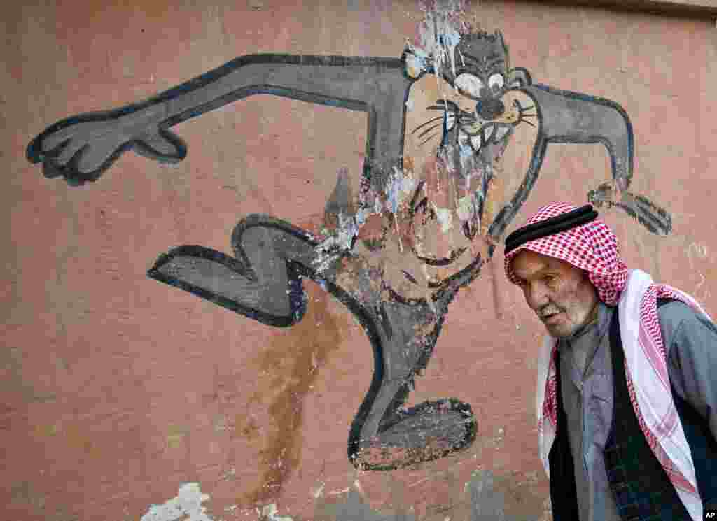 An elderly man walks past a cartoon character painted on a school wall in Suruc, near the Turkey-Syria border, across from the Syrian town of Kobani. 
