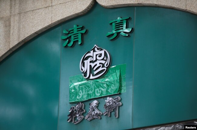 Papan nama sebuah restoran halal yang menggunakan aksara China, tampak ditutup kain di Niujie, Beijing, China, 19 Juli 2019. (Foto: Reuters)