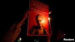 FILE - People hold placards and candles Sept. 6, 2017, during a vigil for Gauri Lankesh, a senior Indian journalist shot dead outside her home by unidentified assailants in southern city of Bengaluru, in Ahmedabad, India.