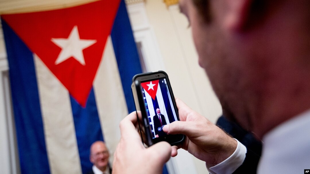 A visitor poses for a photograph in front of the last Cuban flag that was lowered from the Cuban Embassy in Washington on Jan. 3, 1961, when relations between the United States and Cuba were severed, in their new embassy in Washington, July 20, 2015.