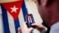 A visitor poses for a photograph in front of the last Cuban flag that was lowered from the Cuban Embassy in Washington on Jan. 3, 1961, when relations between the United States and Cuba were severed, in their new embassy in Washington, July 20, 2015.