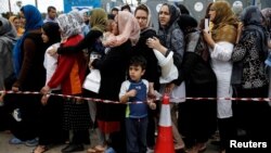 Migrants line up to receive personal hygiene goods distributed by the U.N. High Commissioner for Refugees, outside the main building of the disused Hellenikon airport where stranded refugees and migrants, most of them Afghans, are temporarily accommodated