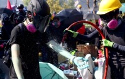 Anti-government protesters clean blue liquid from the police's water cannon outside Hong Kong Polytechnic University in Hong Kong, Nov. 17, 2019.