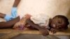 FILE - A girl grimaces as a health worker extracts a parasitic worm from her at a containment center in Savelugu, Ghana.