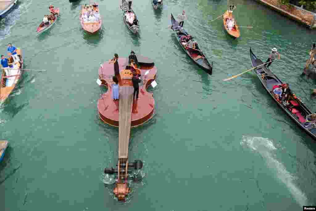 A string quartet plays onboard a violin-shaped boat, titled &quot;Violin of Noah&quot;, that was built by artist Livio De Marchi in collaboration with Consorzio Venezia Sviluppo and is dedicated to people who have died from the disease, in Venice, Italy, Sept. 18, 2021.